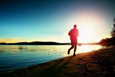 Tall man in running cloths  at amazing sunset in sport and healthy lifestyle concept and jogging cross country training workoutの写真素材
