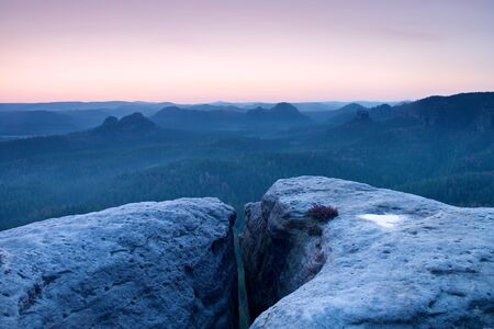 Morning view over sandstone cliff into forest valley, daybreak Sun at horizon. Hills increased from foggy backgroundの写真素材
