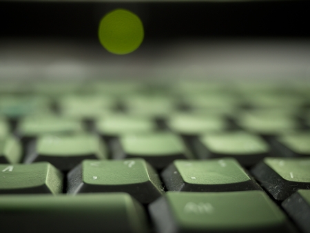 Close up detail view of heavy used and dirty laptop computer keyboard in green shadowsの写真素材
