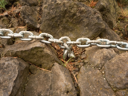 Eye bolt with iron chain anchored into sandstone rock. Twisted chain of climber safety path fixed in block by screws snap hooks.の写真素材