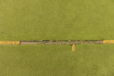 Defects in playground. Damaged lines in outdoor handball court. Hairy plastic light green surface on ground and white, red and blue bounds lines.の写真素材