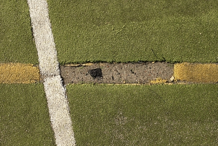 Defects in playground. Damaged lines in outdoor handball court. Hairy plastic light green surface on ground and white, red and blue bounds lines.の写真素材
