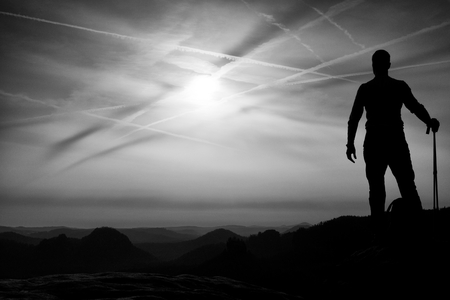 Tourist with poles in hands stand on a rock watching for next step. Sunny spring daybreak in mountains.Vignetting effect ..の写真素材
