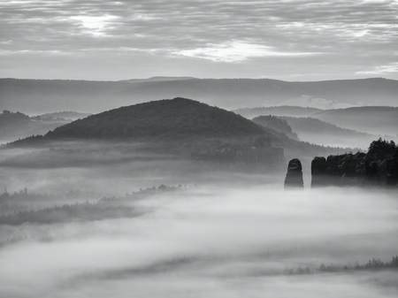 Fantastic sunrise on the top of the rocky mountain with the view into misty valley. Black and white photoの写真素材