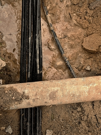 Building of lines of metallic and fiber optic cables, construction of communication optical network connection. Laying underground tow cable. Excavation of trench by hand or mechanized excavator and installation.の写真素材