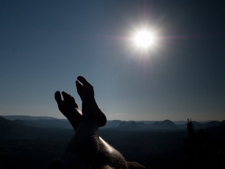 Naked male hairy legs take a rest on peak of rock. Outdoor activities in hot summer weather, muggy...