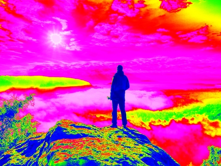 Amazing thermography photo. Professional photographer with tripod in hands on cliff and thinking. Dreamy fogy landscapeの写真素材