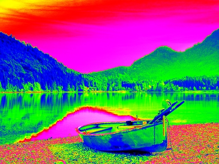 Amazing thermography photo. Abandoned fishing paddle boat on bank of Alps lake. Morning lake glowing...