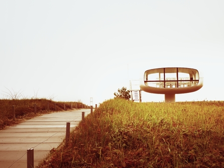 Tourist atractiion, caffe room at sea shore with round view. Wooden board to offshore, old grass.の写真素材