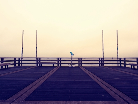 Abandoned seaside Telescope. Autumn misty morning on wooden pier above sea. Depression, dark...
