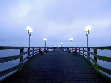 Autumn dark mist on wooden pier above sea. Depression, dark atmosphere. Touristic mole, wet wooden...