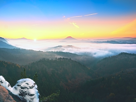 Cocks covered with fresh powder snow, misty valley. Stony rock peak increased from foggy valley. Winter misty sunrise in a beautiful rocks empire.の写真素材