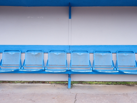 New blue metal seats on outdoor stage players bench, chairs with blue paint wooden roof below.の写真素材