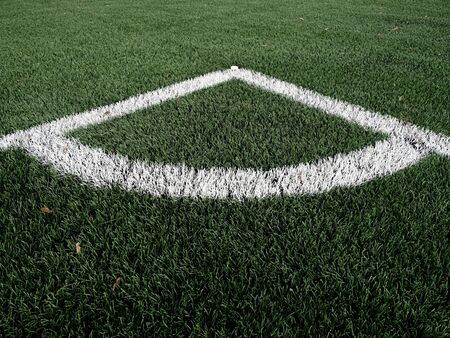 Football playground corner on heated artificial green turf ground with painted white line marks....