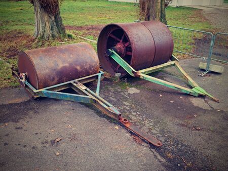 Old rusty iron barrel for maintenance of neglect football playground. Old asphalt surface on outdoor parking placeの写真素材