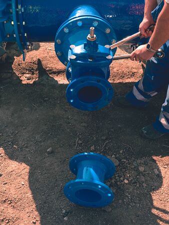 Worker hands screwing Gate valve with nuts on new dring water piping. Water suply with new...