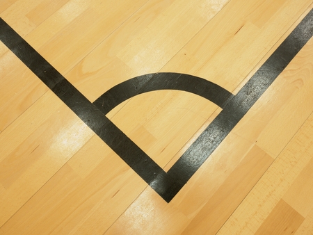 Black corner. Worn out wooden floor of sports hall with colorful marking linesの写真素材