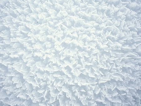 Stucture of crystal snow surface from very close distance. Frozen snow flakes stick together into rough sharp structureの写真素材