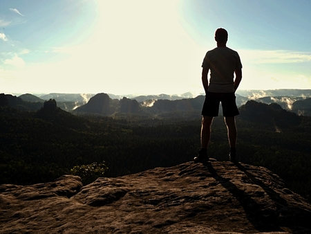 Tourist man on cliff of rock in rock empires park is watching over creamy mist and foggy morning valley to Sunの写真素材