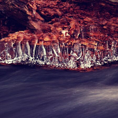 Close up view of structured ice above and motion blur water stream. Creative winter long exposure photography.の写真素材
