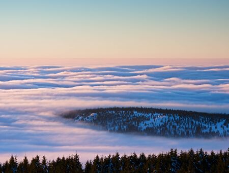 Inverse weather in mountains, shinning fog. Misty valley in winter mountains. Peaks of  mountains...