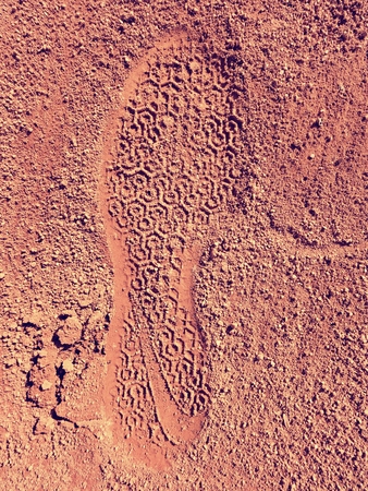 Detail with a sport shoe footprint on a tennis clay court. Dry light red crushed bricks surface on outdoor tennis groundの写真素材