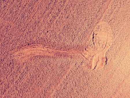 Detail with a sport shoe footprint on a tennis clay court. Dry light red crushed bricks surface on outdoor tennis groundの写真素材
