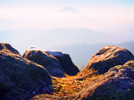 Rocky peak above inverse mist. Winter cold weather in mountains, colorful fog. Misty valley in winter mountains. Peaks of  mountains above creamy mist.の写真素材