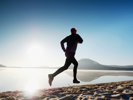 Man running at seaside twilight time. Runner athlete running at seaside. Sportsman fitness silhouette sunrise jogging workout wellness concept. の写真素材