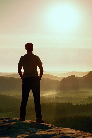 Hiker in black stand on the peak in rock empires park and watching over the misty and foggy morning valley to Sun.の写真素材