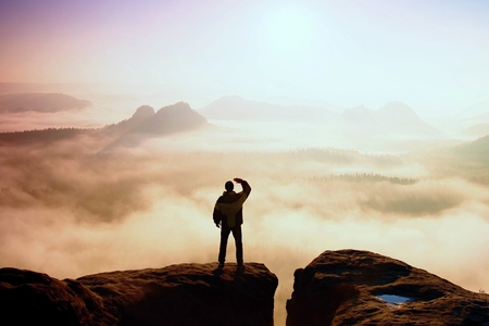 Man stands on the peak of sandstone rock in national park Saxony Switzerland and watching to Sun. Beautiful moment the miracle of natureの写真素材