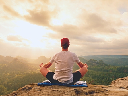 Yoga practicing  at mountain summit with aerial view of the mountain valley. Tall sportsman practicing yoga and meditation in mountains during luxury sunrise.の写真素材