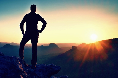 Man stands on the peak of sandstone rock in national park and watching to Sun. Beautiful moment the miracle of natureの写真素材