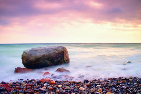 Romantic atmosphere in peaceful morning at sea. Big boulders sticking out from smooth wavy sea. Pink horizon with first hot sun rays.Vintage Style Toned effectの写真素材