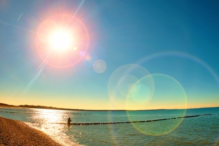 Fisher with rod in golden sunshine with beautiful sea. Fishing at breakwaters in cold Baltic sea. Vivid and strong vignetting effect..の写真素材