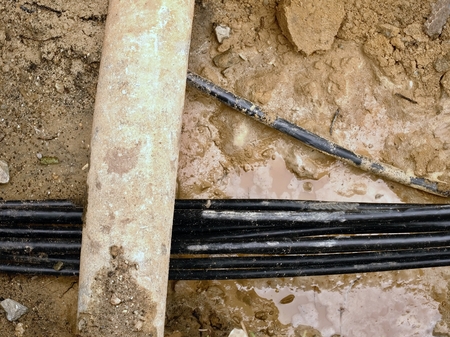 Building of lines of metallic and fiber optic cables, construction of communication optical network connection. Laying underground tow cable. Excavation of trench by hand or mechanized excavator and installation.の写真素材