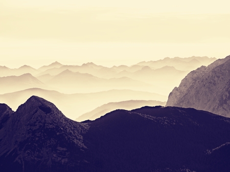 View over high sharp mountain peaks from plane, beautiful view. Fantastic dreamy sunrise, sharp contour of mountain above mist. Dreamy unlear view.の写真素材