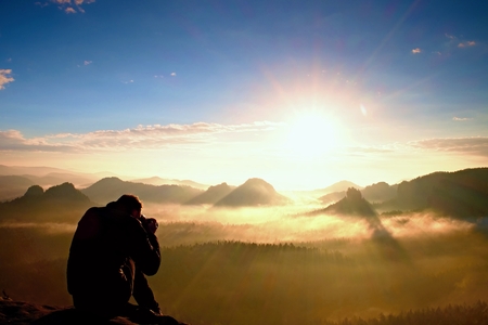 Photographer silhouette above a clouds sea, misty mountainsの写真素材