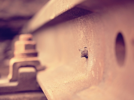 Selective field of focus. Detail of rusty screws and nut on old railroad track. Concrete tie with rusty nuts and bolts. Damaged surface of rail rod. No train passed this railroad for a long time.の写真素材