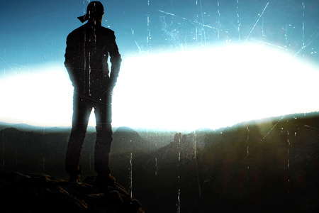 Film grain effect. Hiker in a long cap on a rock peak in the rock empires and watching over the...