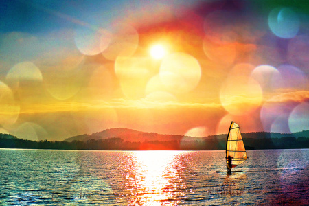 Film grain effect. Windsurfer leans back into breeze Shot with gentle filter. Strong sun makes reflections in mirror of water level.の写真素材