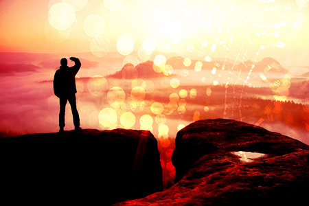 Film grain effect. Happy hiker is standing on the peak of  rock empires park and watching over the misty and foggy morning valley to Sun.の写真素材