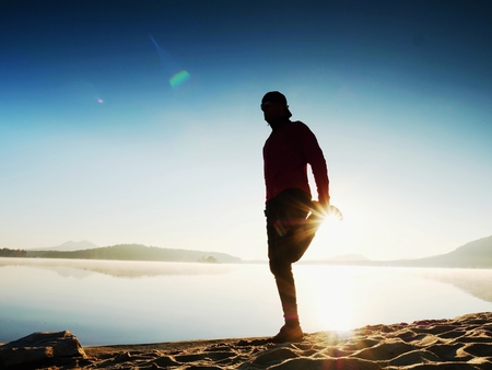 Stretching after jogging. Middle age sports man do stretching pose and deep breatch. Outdoor training at offshore, people and lifestyle concept.の写真素材
