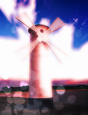 Film grain effect.  White old lighthouse decorated as windmill by sea on rocky coast. Seascape and...