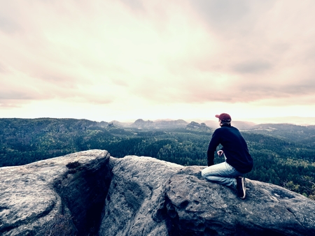 Man tourist sit on a mountain peak. Travel mountain scene. Hiker has a rest on the mountain and...