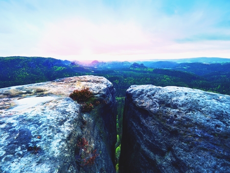 Morning view over sandstone cliff into long  forest valley, daybreak Sun at horizon. Forest hills above fog. Vintage effect.の写真素材