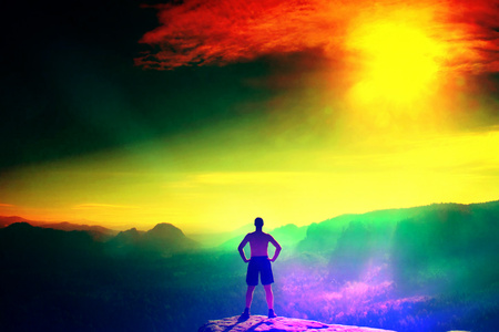Film grain effect. Climber in black pants. Gesture of triumph. Body naked man on the peak of sandstone rock in national park Saxony Switzerland watching into misty landscape.の写真素材