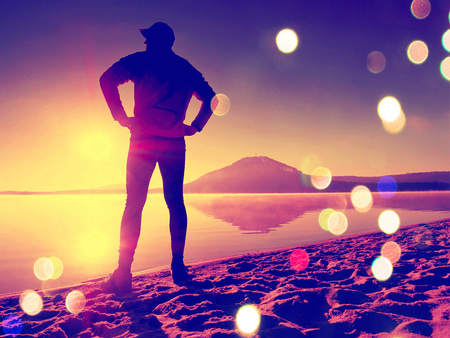 Film grain effect. Man exercising on the beach.  Silhouette of active man exercising  and stretching...