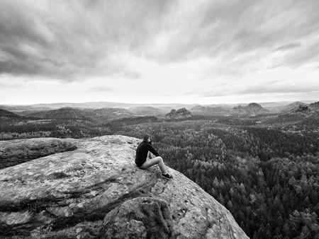 Looking to horizon. Man sitting on a rock above the dense forests or jungles and enjoy the view.の写真素材