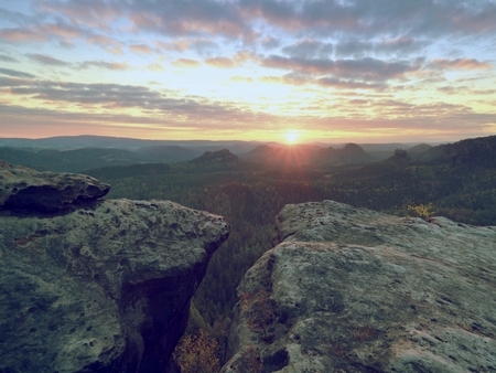 Morning view over crack sandstone edge into forest valley, daybreak Sun at horizon. Hike in natural park. Image is filteredの写真素材